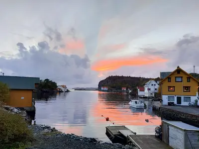 a view of a body of water with a sunset at Charming Cottage At The Edge Of The Sea in Lykling