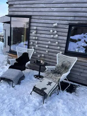 a patio with two chairs and a table in the snow at Architect Drawn Cabin Between Sea And Mountain in Hosen