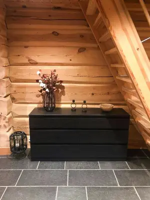 a black dresser with a vase of flowers on it at Spacious Log Cabin Near Hardangervidda in Uvdal