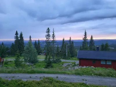 a red barn in the middle of a field at Sunny Cabin With Panoramic Views At Sjusjøen in Sjusjøen