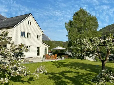 a white house with a yard with a tree at Charming House In Loen, In The Heart Of Nordfjord in Loen