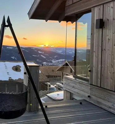 a hammock on a deck with the sunset in the background at Ski Inski Out-Hytte I Hafjell Med Udsigt in Øyer