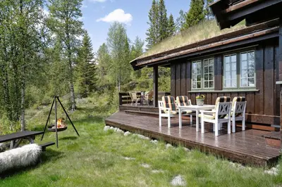 a cabin with a deck with a table and chairs at Mountain Cabin With Great Views in Austbygdi