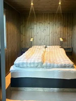 a large bed in a wooden room with two lamps at Idyllic Cabin With Panoramic Mountain Views in Nerskogen