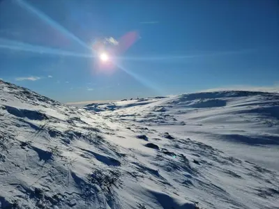 a snow covered mountain with the sun in the sky at Mountain Cabin With Stunning Views, Sauna & Lake in Eggedal