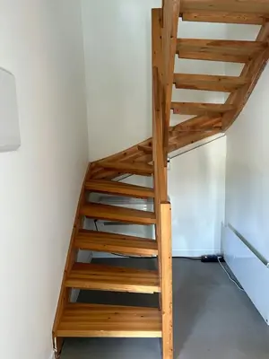 a wooden staircase in a room with a white wall at Charming Seaside Cabin With Views Over The Water