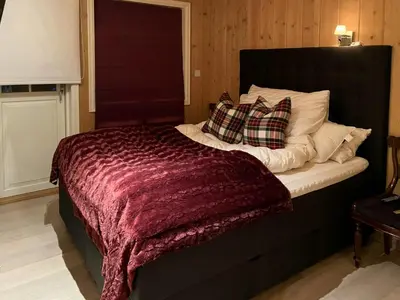 a bed with a burgundy blanket and pillows on it at Mountain Cabin With Sauna, Jacuzzi And Views in Nord Torpa
