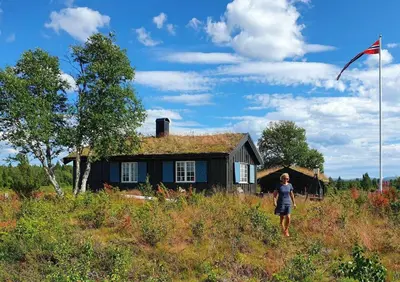 a person flying a kite in front of a house at Mountain Cabin With Wood-Fired Sauna And A View in Golsfjellet