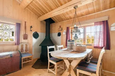a dining room with a wooden table and a stove at Mountain Cabin With Wood-Fired Sauna And A View in Golsfjellet