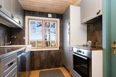 a kitchen with wooden walls and a window at Mountain Cabin With Wood-Fired Sauna And A View in Golsfjellet