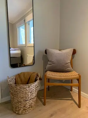 a mirror and a chair with a pillow in a room at Central and modern apartment in Hamar