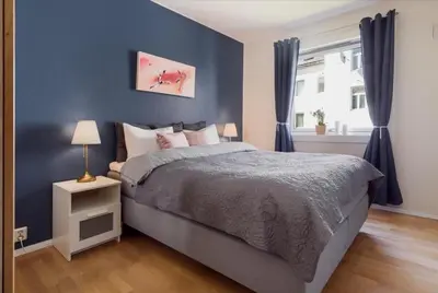 a blue bedroom with a bed and a window at Sentral leilighet Trondheim in Trondheim