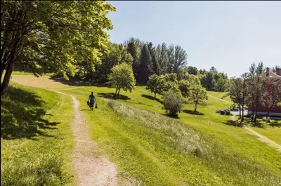 a person walking down a dirt road in a field at Sentral leilighet Trondheim in Trondheim