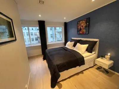 a bedroom with a bed and two windows at Apartment by Torgalmenningen in Bergen