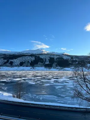 a view of a frozen river with mountains in the background at Voss Apartment in Oppheim Resort, pool and view in Vossevangen