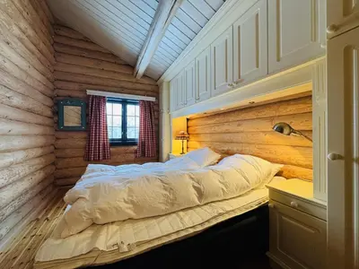 a bed in a room with a wooden wall at Large, cozy, and spacious cabin in Geilo in Geilo