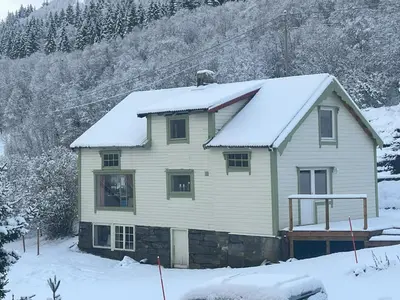 a house with snow on the roof at Fiskesenter Birkeland Guesthouse in Vestnes