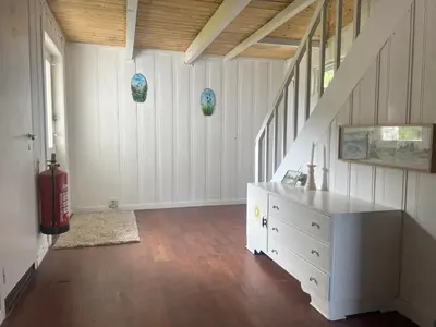 a living room with a white dresser and a staircase at Fiskesenter Birkeland Guesthouse in Vestnes