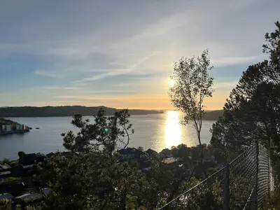 a sunset over a body of water with trees at Cozy studio near Bergen in Bergen