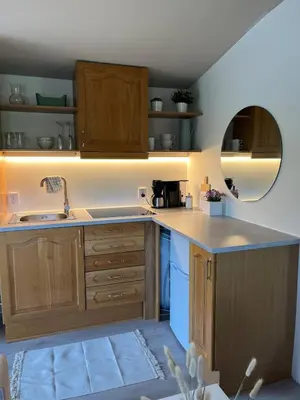 a kitchen with wooden cabinets and a sink and a mirror at Cozy studio near Bergen in Bergen