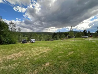 a large grass field with two cars parked in it at Turifoss Camping Tent pitch in Svedjan