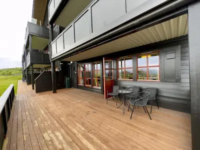 a building with a deck with chairs and a table at Homey Apartment Steps From Dining And Activities! in Beitostøl