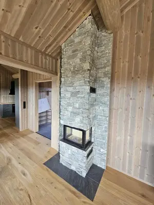 a stone fireplace in a room with a wooden ceiling at Varden in Sør-Fron