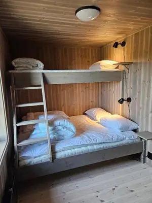 two bunk beds in a wooden room with a ladder at Utsikten in Sør-Fron