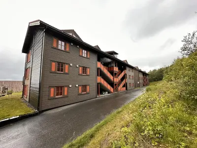 a black building with orange windows on a road at Central Apartment With Garage, Views, Ski In And Out in Beitostøl