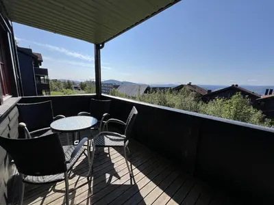 a patio with tables and chairs on a balcony at Central Apartment With Garage, Views, Ski In And Out in Beitostøl