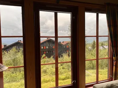 a room with four windows with a view of a house at Central Apartment With Garage, Views, Ski In And Out in Beitostøl