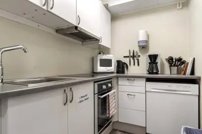 a kitchen with white cabinets and a sink and a microwave at 1-roms leiligheter med felles bad, stue og kjøkken in Steinkjer