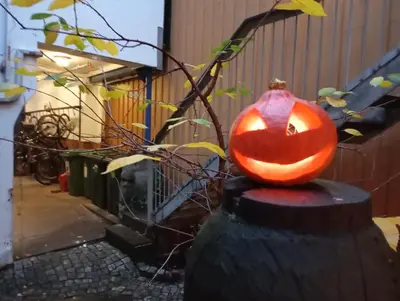 a pumpkin carved into a face sits on a fence at Nice two-floor home by Gamle bybro in Trondheim