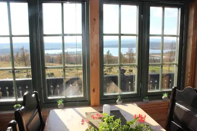 a dining room with a table and chairs and windows at Hytteperle Gålå, Vakre Lauvåsen, Hønhuset in Sør-Fron