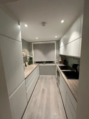 a kitchen with white cabinets and a large window at Leilighet på Byåsen, i nærheten av Granåsen in Trondheim