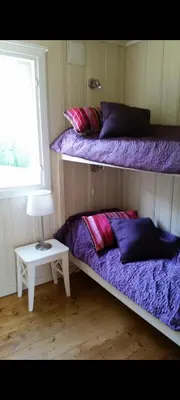 a room with two bunk beds and a table with a lamp at Holiday house by Lake Mjosa, 4 beds in Eidsvoll
