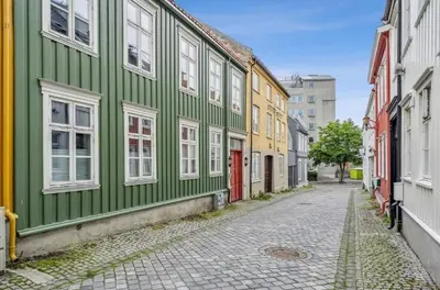 a narrow street with green and yellow buildings at Newly renovated apartment in the middle of Trondheim city centre in Trondheim