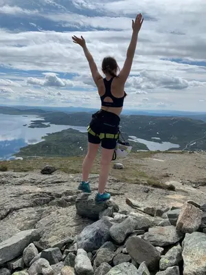 a woman standing on top of a mountain with her arms up at Bjørndalenhytta in Beitostøl