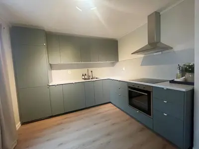 a kitchen with green cabinets and a stove top oven at Newly renovated apartment for rent in Stjoerdal