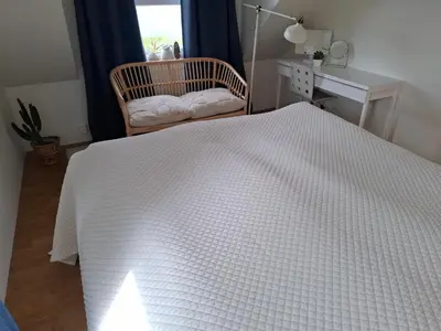 a bedroom with a white bed with a chair and a window at Close to the Airport and Trondheim in Malvik