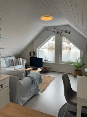 a living room with a couch and a large window at Sjøro in Forland