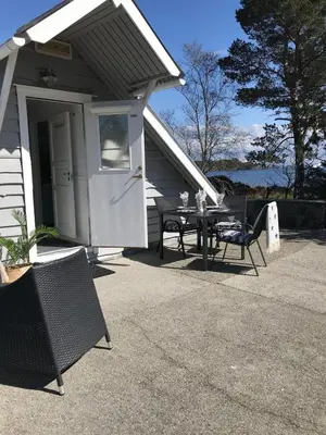 a patio with a table and chairs in front of a house at Sjøro in Forland