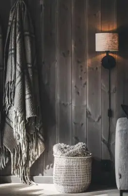a room with a wicker basket and a lamp and a wall at Cozy ski in & out apartment in Kyrkjebøen