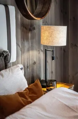 a bedroom with a bed and a lamp on a table at Cozy ski in & out apartment in Kyrkjebøen