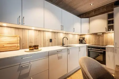 a kitchen with white cabinets and a sink at Cozy ski in & out apartment in Kyrkjebøen