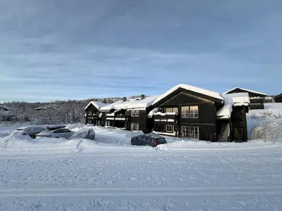 a snow covered house with cars parked in the snow at Beitotind 1504 in Beitostøl