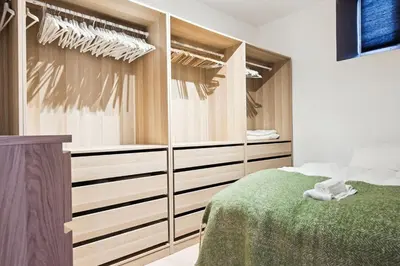 a bedroom with wooden cabinets and a green bed at Sjarmerende leilighet med utsikt, spa-bad og park in Bergen