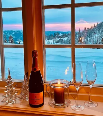 a bottle of wine and glasses on a window sill at Cozy cabin apartment, ski-in ski-out at Kvitfjell in Kvitfjell