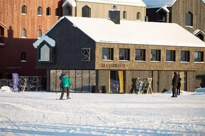 a person is standing in the snow in front of a building at Ski in-out - 3BR, 2 Bath Chalet apartment - Favn Hafjell in Hafjell