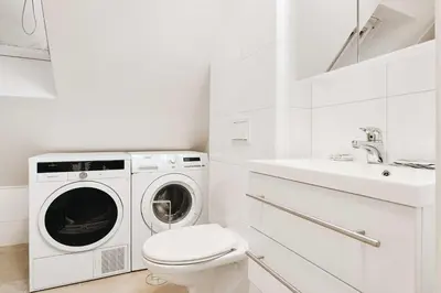 a white bathroom with a washing machine and a sink at 200m to Torgalmenningen & 20 sqm terrace in Bergen